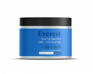 A bottle of Everest Full Spectrum CBD gummies sitting on a wooden table.