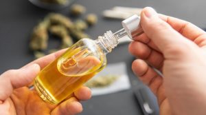 A bottle of golden Synthetic THC Vape Oil resting next to a modern vaporizing mod.
