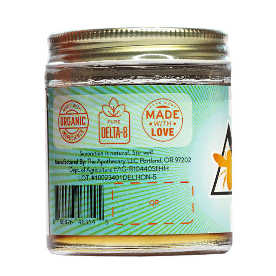 An elegant glass retail jar with a colorful label containing gold-colored premium Delta 8 Honey Gummies candies